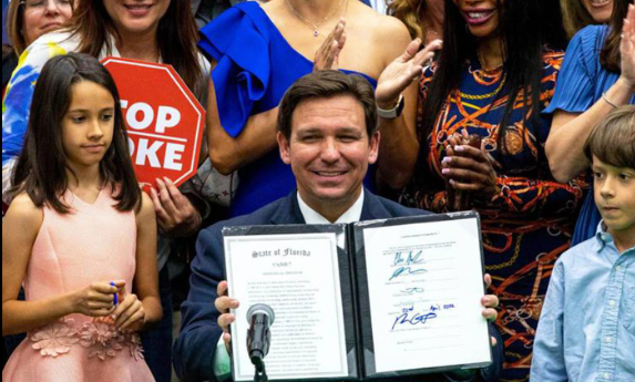 Florida's anti-woke governor smiles while children sadly look on confused